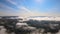 Aerial view from high altitude of landscape covered with puffy morning fog. Cold humid air condensing in rain clouds