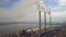 Aerial view of high chimney pipes with grey smoke from coal power plant. Production of electricity with fossil fuel.