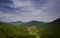 Aerial View Hilly Jungle Distant River under Blue Sky