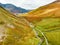Aerial view of Honister Pass, a mountain pass with a road winding along Gatesgarthdale Beck mountain stream. Cumbria, the Lake