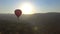 Aerial view of hot air balloon flying over mountain village at beautiful sunset