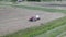 Aerial view how tractor making bales with with white film