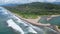 Aerial view of an idyllic Caribbean beach with a lush, green forest bordering a bright blue ocean