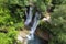 Aerial view of an Idyllic rain forest waterfall, stream flowing in the lush green forest.