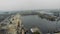 Aerial view of industrial grey city covered in fog and smog. Cargo trains and railway station near river docks and cargo port cran