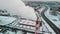 Aerial view of industrial zone with large red and white pipes with white smoke. Smoke is poured from the factory pipe in