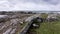 Aerial view of irish coast, green fields, rocks, rough sea in the background in a cloudy day. Rocky walls constructions