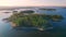 Aerial view of an island on a lake with tourists in boats and kayaks. Blue lake, islands, rocky shore and green forest