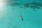 Aerial view of a kayak on the turquoise sea, An aerial view of a woman on a surfboard in the turquoise waters of the Maldives, AI