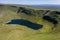 Aerial view of a lake formed at the base of green mountains Llyn y Fan Fach, Brecon Beacons, Wales