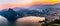 Aerial view of the lake Lugano surrounded by mountains and evening city Lugano on during dramatic sunset, Switzerland, Alps.