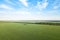 Aerial view of a landscape in fields with agricultural plants for growing green vegetables and cereals under blue sky in summer.