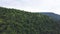 Aerial view of large mountain covered by green lush trees. Clip. Natural landscape with beautiful forested hills, summer