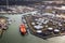 Aerial view of a large orange oil tanker moored at an oil storage silo terminal in an industrial port