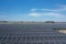 Aerial view of a large-scale solar farm with an array of black solar panels arranged in neat rows