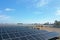 Aerial view of a large-scale solar farm with an array of black solar panels arranged in neat rows