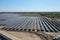 Aerial view of a large-scale solar farm with an array of black solar panels arranged in neat rows