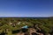 Aerial view of a large villa with a pool and a backyard full of trees and vegetation on a sunny day