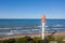 Aerial view of lighthouse with red top and white base. Blue sky and sea. Pape lighthouse