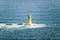 Aerial view of lighthouse at sea surrounded by water on Maine coastline, south of Portland