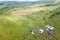 Aerial view of livestock plots and agricultural green fields in nature in the Altai Mountains with small houses of farm, tractors