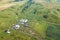 Aerial view of livestock plots and agricultural green fields in nature in the Altai Mountains with small houses of farm, tractors