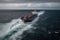 Aerial view of a loaded container cargo ship as it speeds over the ocean.