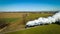 Aerial view of a locomotive traveling across the rural landscape with lush green pastures