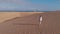 Aerial view - a lonely girl walks and then runs through the desert, Maspalomas, Gran Canaria