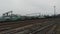 Aerial view of long freight cargo train with wagons and fuel tanks moving through industrial city train station.