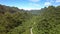 Aerial View Long Modern Road Meanders at Foot of Green Hills