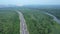 Aerial view of lush green area with water body and cars moving on the road