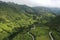 Aerial view of a lush green valley with a dirt road running through the meadows in the andean mountains of Ecuador