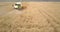 Aerial view machine grabs wheat with rakes against horizon