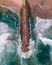 Aerial view of a majestic breakwater with rough rolling water waves rolling on the beach at Costa da Caparica, Setubal, Portugal