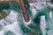 Aerial view of a majestic breakwater with rough rolling water waves rolling on the beach at Costa da Caparica, Setubal, Portugal