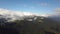 Aerial view of majestic mountains covered with green spruce forest and high snowy peaks.