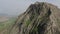 Aerial view of majestic rock with green vegetation against misty valley at background. Splendid wild nature in highlands