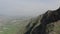 Aerial view of majestic rock with green vegetation against misty valley at background. Splendid wild nature in highlands