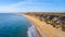 An aerial view of a majestic seacoast hill with huge cliff, sandy beach, groyne breakwater and crystal blue water under a