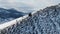 Aerial view of a man with a backpack climbing the slope of a mountain covered with snow against the backdrop of a