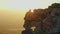 Aerial view. A man sits on a rock on the background of the valley filled with sunset and the silhouettes of mountains