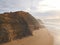 Aerial view from a man walking sandy beach at the sunset with an amazing cliff