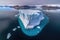 aerial view of massive iceberg floating away from glacier