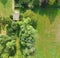 Aerial view of a meadow bordering a lawn, with a shed and several bushes and trees