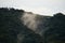 Aerial view of mist, cloud and fog hanging over a lush tropical rainforest after a storm. Treetops of mountain range with fog