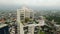 Aerial view of modern high-rise with green rooftop terraces over urban skyline. Sustainable living spaces in city