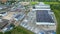 Aerial view of modern storage warehouse with solar panels on the roof. Logistics center in industrial city zone from drone view.