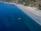 Aerial view of moored boat floating on a transparent sea. Nonza black beach. Corsica. France