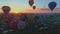 Aerial view of a morning launch of hot air balloons at a hot air balloon festival at sunrise on a sunny summer day